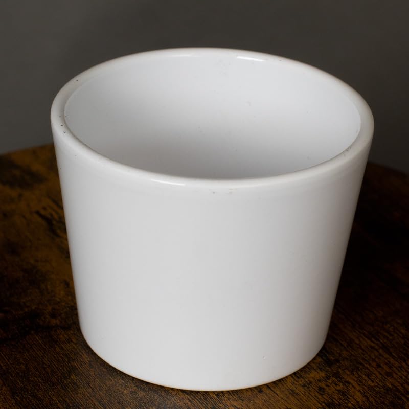White ceramic cup on a dark wooden surface with a dark background