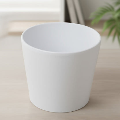 Indoor houseplant pots displayed in a bright interior setting, featuring a white ceramic plant pot with a smooth minimalist design.